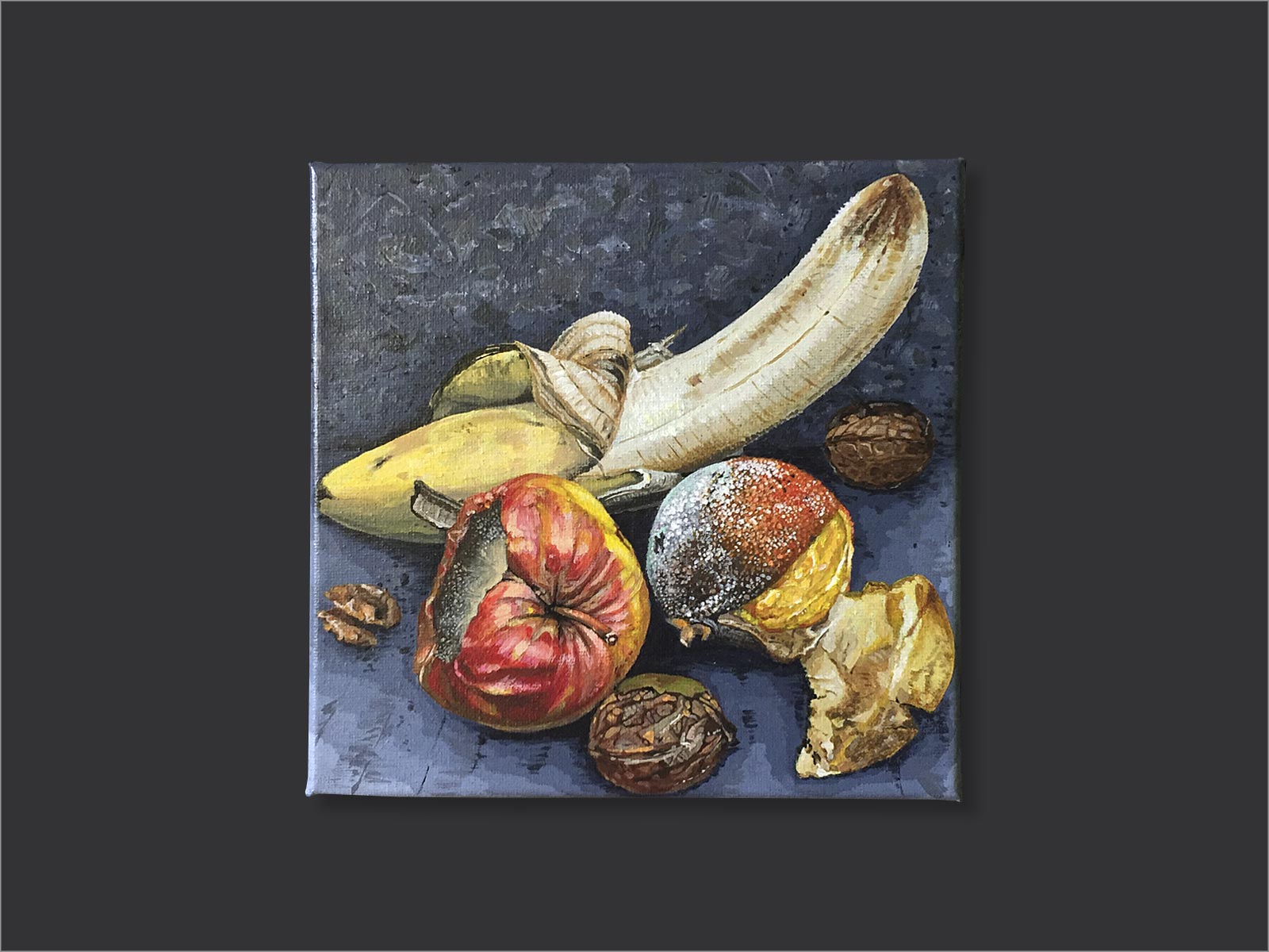 compositie van een banaan, appel, sinaasappel en walnoten waarbij het fruit beschimmeld en aangetast is