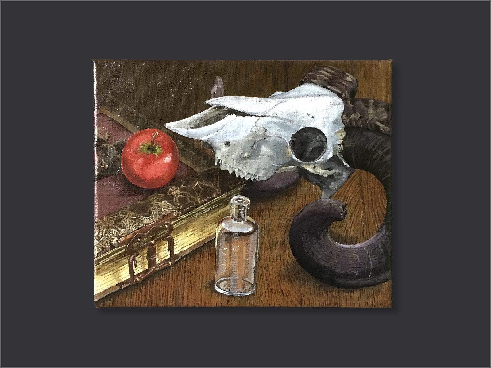 compositie van een antiek boek met slot met hierop een rode appel, met een klein glazen flesje en de schedel van een ram